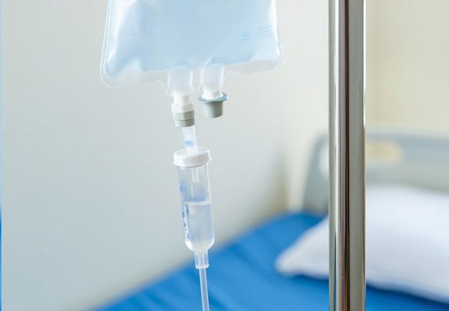 Инфузионный мешок с голубоватой жидкостью и двойным портом висит на металлической стойке